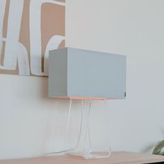 a lamp sitting on top of a wooden table next to a wall mounted art piece