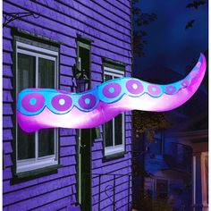 an inflatable object is hanging from the side of a purple house at night