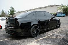 a black car parked in a parking lot next to other cars