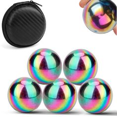 four shiny balls are in front of a black case and one is on the ground