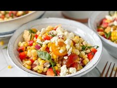 two bowls filled with corn and vegetables on top of a table