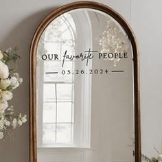 a mirror sitting on top of a table next to a vase filled with white flowers