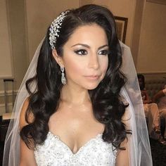 a woman in a wedding dress with a veil on her head is posing for the camera