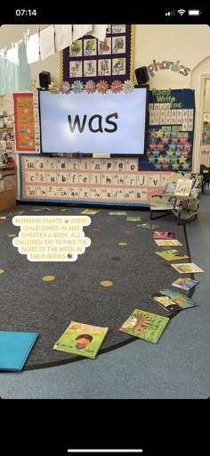 a classroom with lots of books on the floor and a large screen in the middle