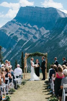 a bride and groom standing at the end of their wedding ceremony with mountains in the background