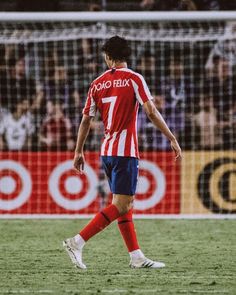 a soccer player is standing on the field with his foot in the air as he looks at the ball