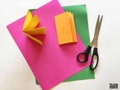 two pieces of paper and scissors on top of each other with colored sheets of paper next to them