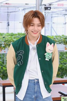 the young man is wearing a green and tan jacket with a cartoon character on it