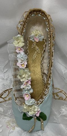 a close up of a shoe with flowers on the bottom and gold trimmings