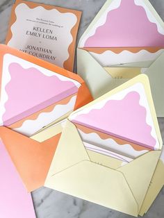 four folded envelopes sitting on top of a marble table next to an open book