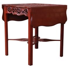 a small wooden table with an intricate design on the top and bottom shelf, sitting against a white background