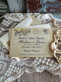 wedding save the date cards on an old lace doily with pearl necklace and pearls