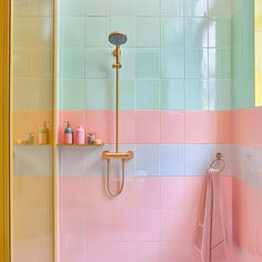 a bathroom with pink, yellow and blue tiles on the walls next to a shower head