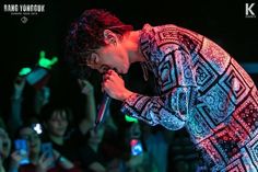 a man standing on top of a stage holding a microphone in front of an audience