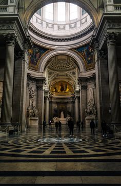 people are standing in the middle of a large room with marble flooring and pillars