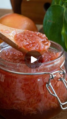 a glass jar filled with jam next to an apple