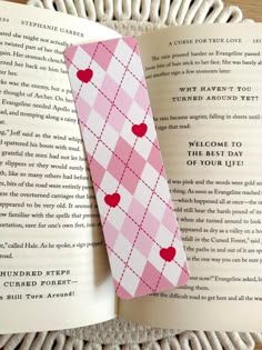 an open book with a pink checkered tie on it