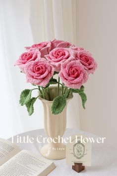 pink flowers in a vase on a table with an open book