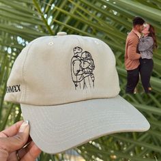 a person holding up a hat with an image of two people kissing on the front