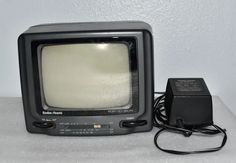 an old black television sitting on top of a white table next to a charger