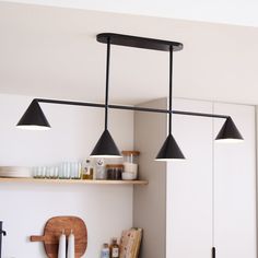 three lights hanging from the ceiling above a counter top in a kitchen with white walls