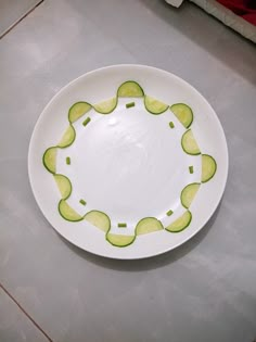 a white plate topped with sliced cucumbers on top of a kitchen counter next to a knife and fork