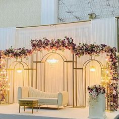 a white couch sitting in front of a flower covered wall with lights on it's sides