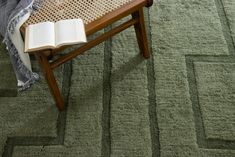 an open book sitting on top of a wooden bench next to a chair and rug