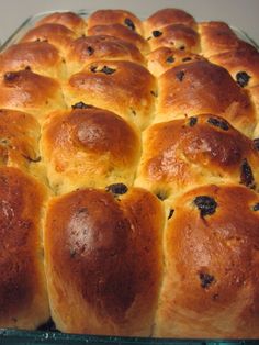 a glass baking dish filled with rolls covered in cheese and raisins