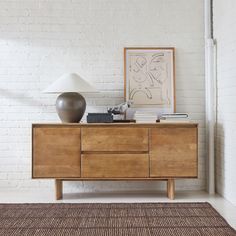 a white brick wall with a wooden dresser and lamp