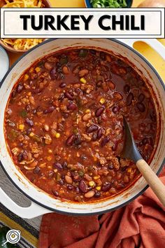 a large pot filled with chili and beans next to other bowls full of food on the table