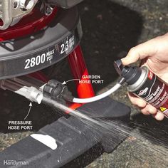 a person is spraying paint on the side of a car's trunk with a hose