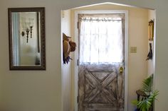 a door with a hat hanging on it's side next to a mirror and potted plant