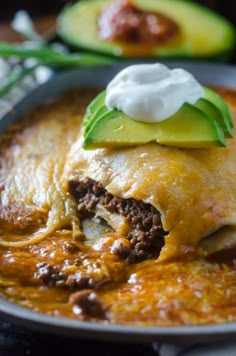 an enchilada with meat, cheese and sour cream sits on a plate