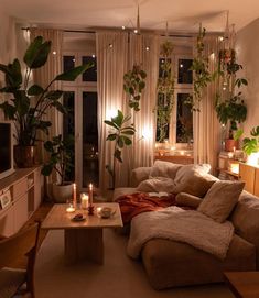 a living room filled with lots of furniture next to a window covered in plants and candles