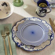 a blue and white plate sitting on top of a table next to gold utensils