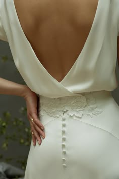 the back of a woman's wedding dress, with her hand on her hip