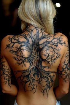 the back of a woman's body with tree tattoos on her upper and lower back