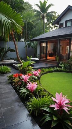 a house with lush green grass and pink flowers in the front yard, surrounded by palm trees