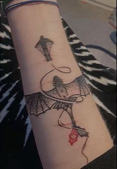 a woman's arm with a tattoo on it that has an image of a man holding a kite