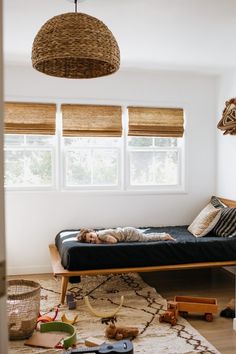 a child laying on a bed in the middle of a room with toys all around