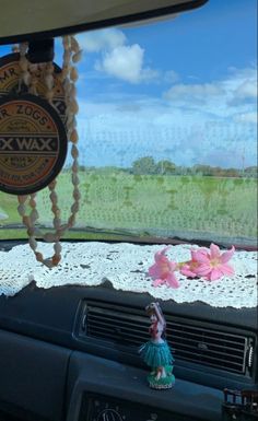 the interior of a car with beads hanging from it's dash board and flowers on the dashboard