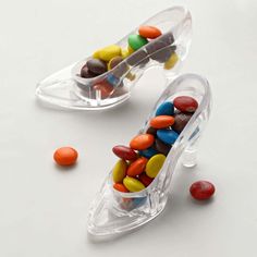 two clear containers filled with candy beans on top of a white table next to each other