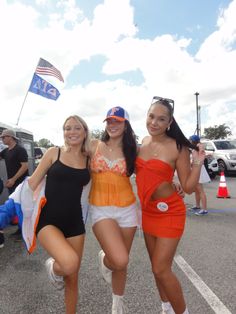 three women in bathing suits posing for the camera with an american flag flying behind them