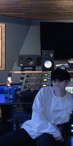 a man sitting in front of a mixing desk with sound equipment on the wall behind him