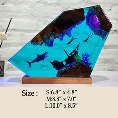 a glass vase with blue and purple fish in it on top of a wooden stand