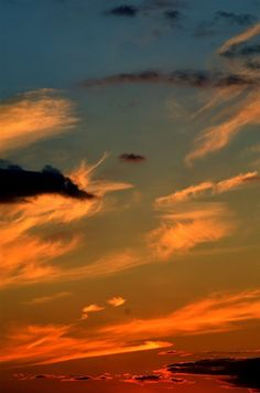 an airplane flying in the sky at sunset with clouds and sun setting on it's horizon