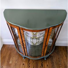 a green glass cabinet sitting on top of a hard wood floor next to a wall