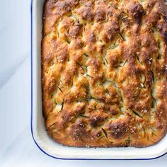 a square casserole dish filled with cheese and rosemary sprinkled on top