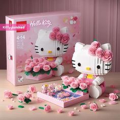 a hello kitty set with pink roses in front of it and a box on the table